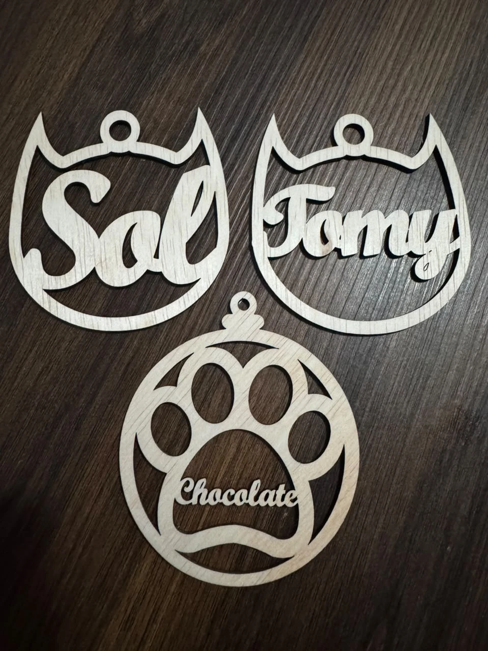 Tres esferas de mascotas en madera natural con los nombres Sol, Famy y Chocolate.